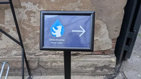 Schild mit Text Drupal Camp Berlin und einem Pfeil, der nach rechts zeigt